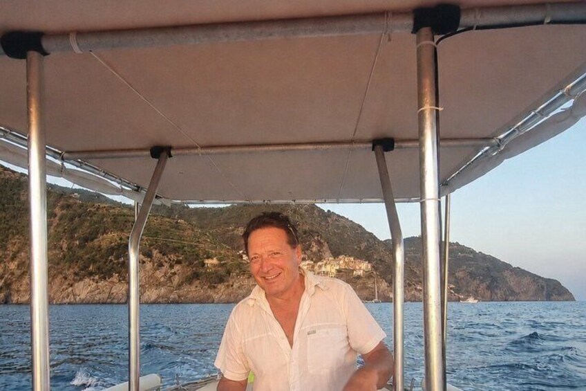 A person on a boat with a rocky coastline in the background. 1