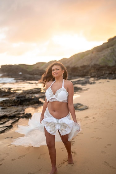 A person standing on a sandy beach with rocky cliffs in the background. 3