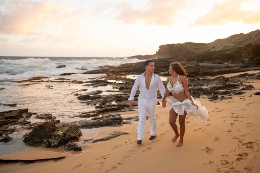 A couple walking on a rocky beach with the ocean in the background. 1