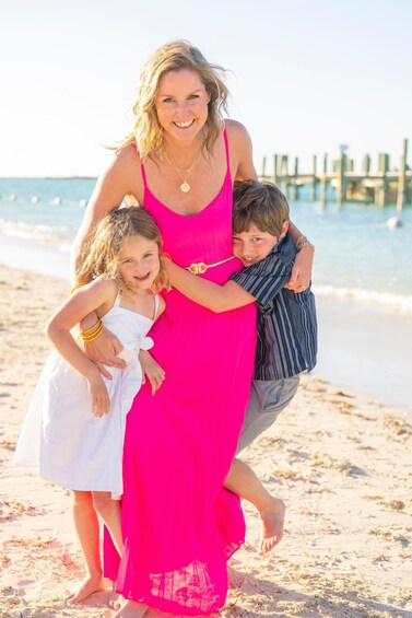 A family on a sandy beach with a wooden pier in the background. 2