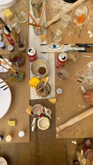 A cluttered workspace with paint cans, brushes, and art supplies. 3