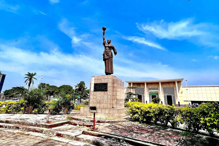 A statue on a pedestal, a building with a sign, and a clear blue sky. 4