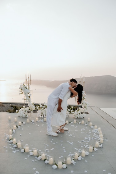 A couple embracing on a beach with a floral arch and candles. 2