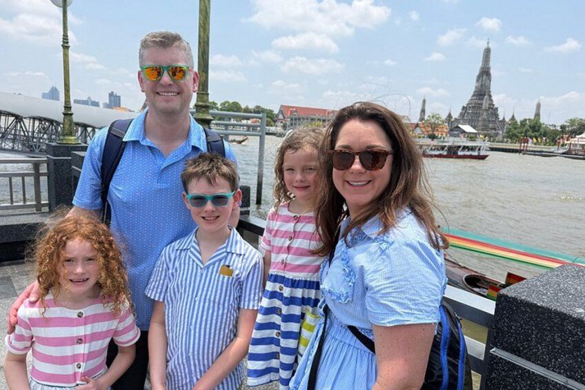 A family on a boat with a river and a temple in the background. 3