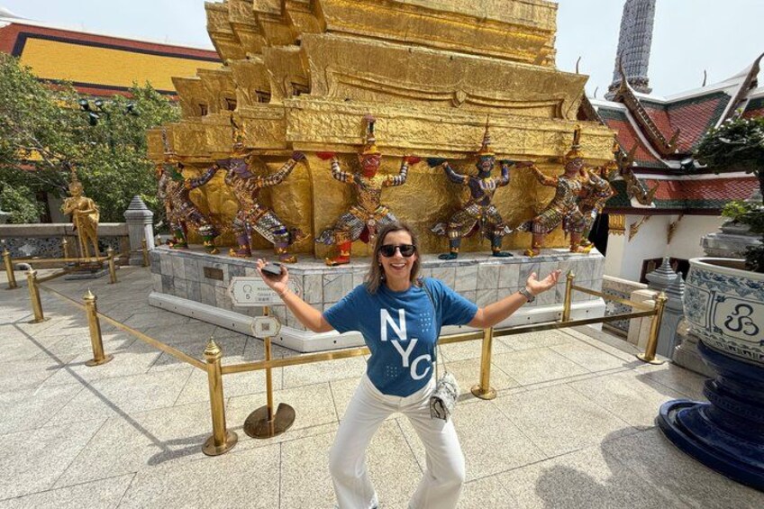 A person in front of a golden structure with statues, wearing a blue shirt with 'NYC' on it, and white pants. 1