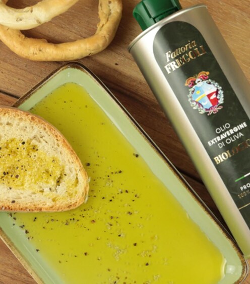 A bottle of extra virgin olive oil, a slice of bread with olive oil, and a green plate. 3