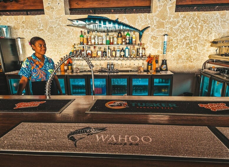 A bar with a fish decoration, a bartender, and a wall with a fish pattern. 5