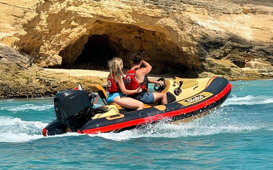 Two people on a jet ski near a rocky coastline. 3