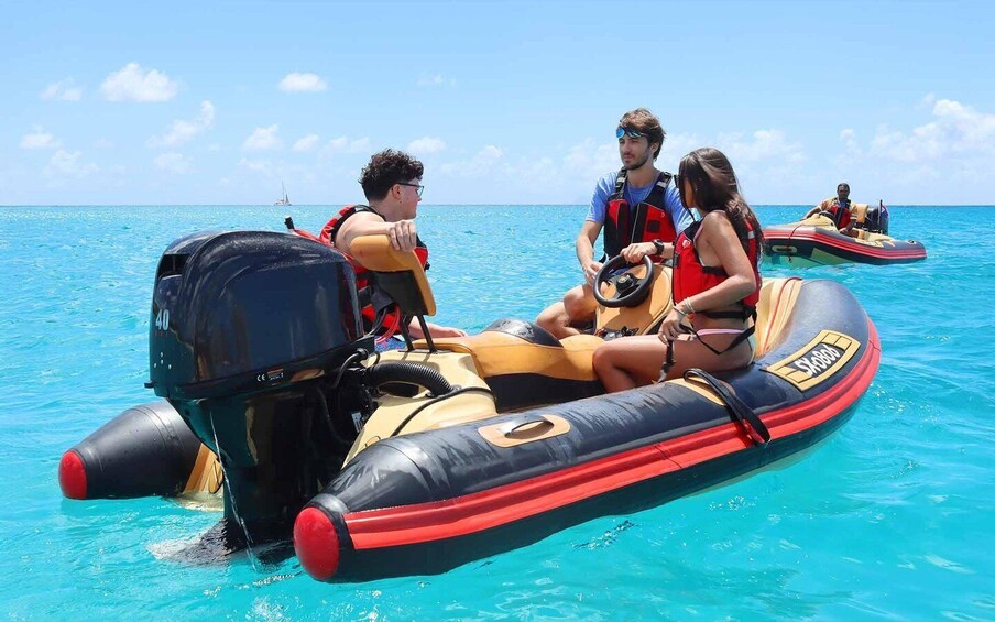 A group of people on a motorized inflatable raft in clear blue water. 4