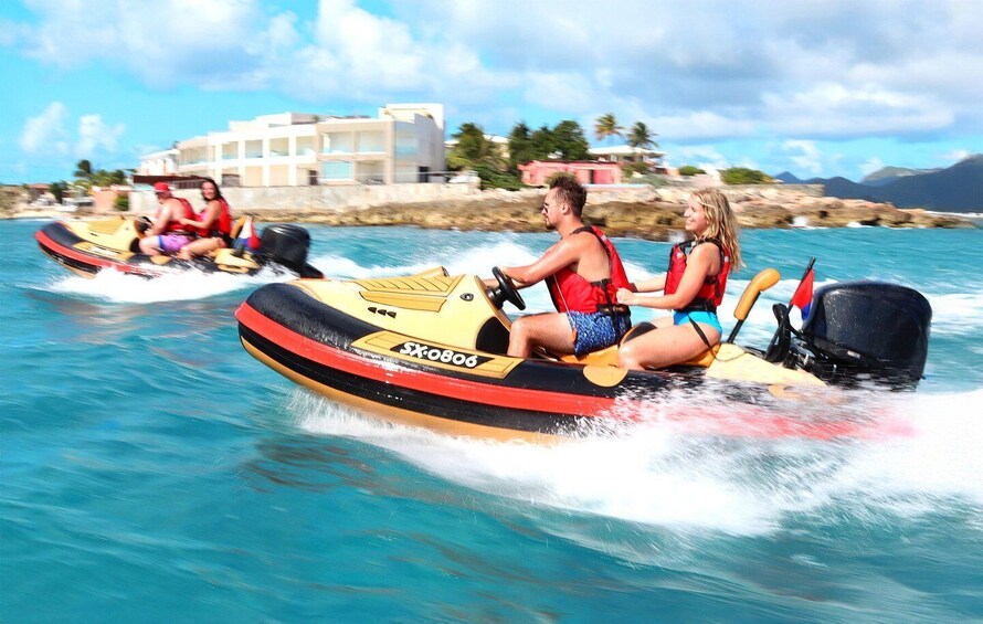 People jet skiing on a clear day with a coastal building in the background. 1