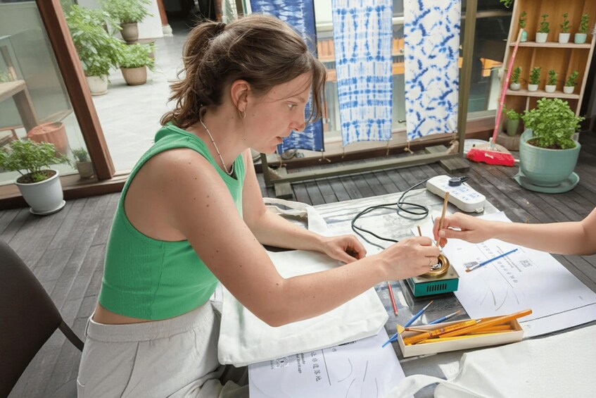 A person working at a table with papers, a box, and drawing tools. 2