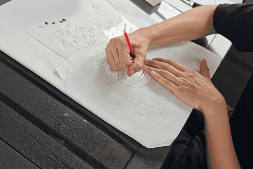 A person drawing on a white sheet of paper with a red pencil. 4