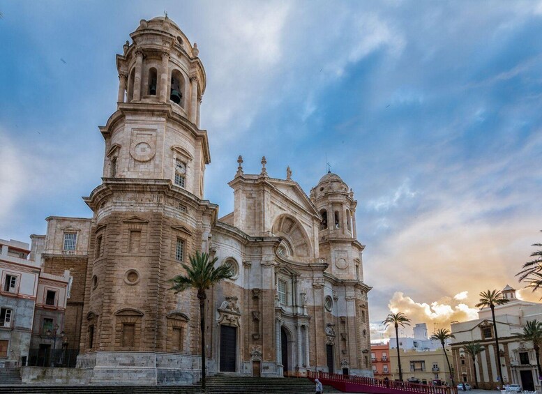 A historic cathedral with a bell tower, palm trees, and a sunset sky. 3