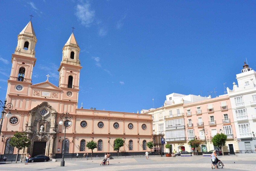 A historic church with two towers, a plaza with pedestrians, and surrounding buildings. 2