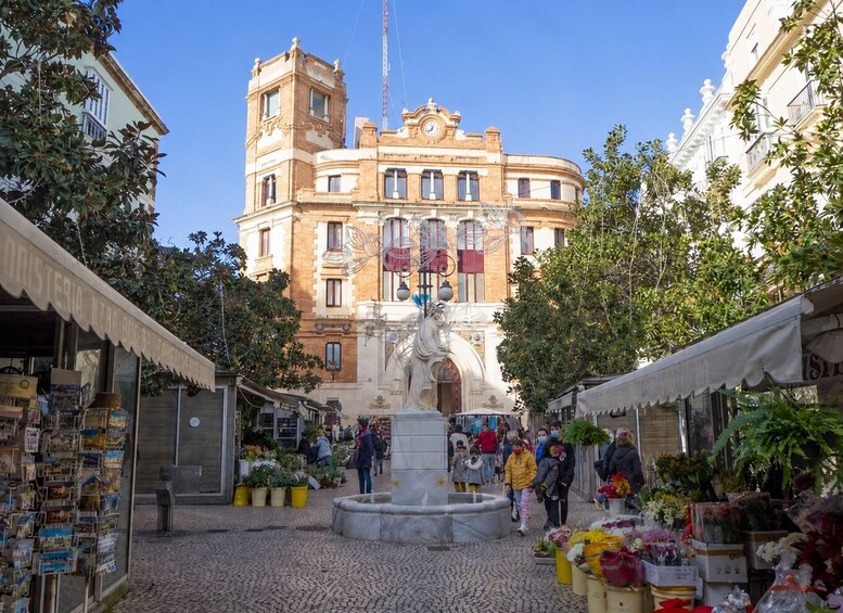 A bustling market square with a fountain, surrounded by shops and a historic building. 4