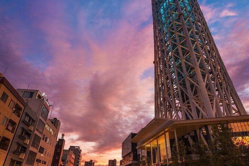 A cityscape with a prominent modern building with a unique lattice structure, surrounded by other buildings and a sunset sky. 3