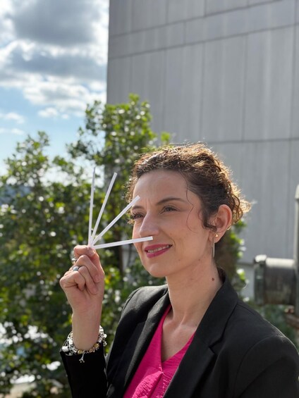 A person holding a paper airplane outdoors with trees and a building in the background. 5