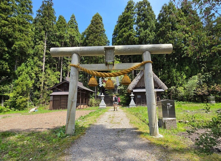 A traditional Japanese torii gate with a rope barrier, surrounded by lush greenery and a clear sky. 4