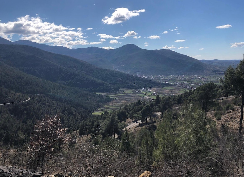 A mountainous landscape with a valley, roads, and scattered buildings. 5