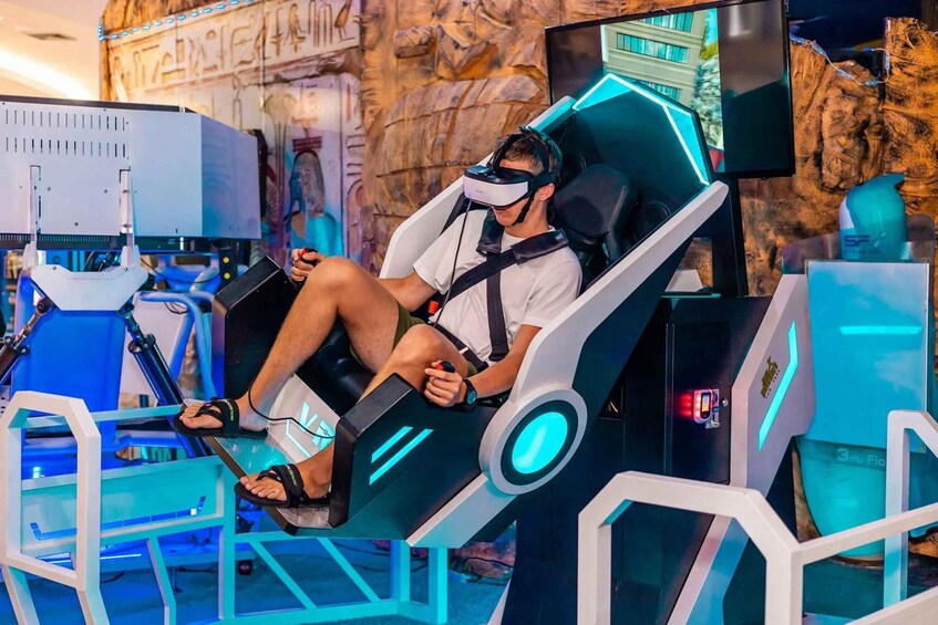 A person seated in a futuristic chair with a VR headset, surrounded by blue and white geometric structures. 1