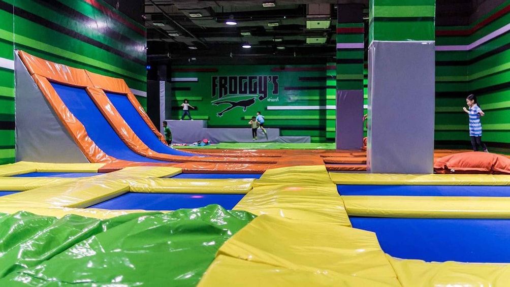 An indoor trampoline park with colorful trampolines and a logo for 'Froggy's.' 5