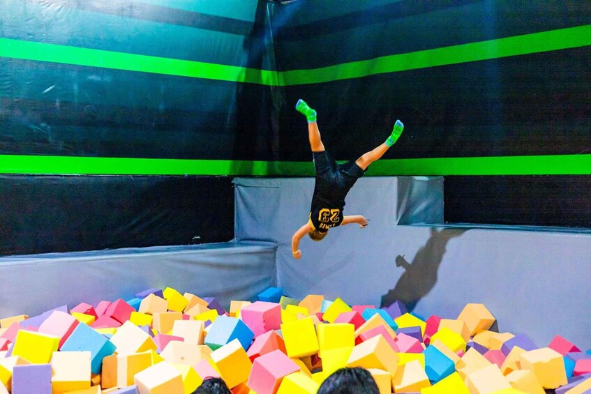 A person performing a handstand in a foam pit with colorful blocks. 5
