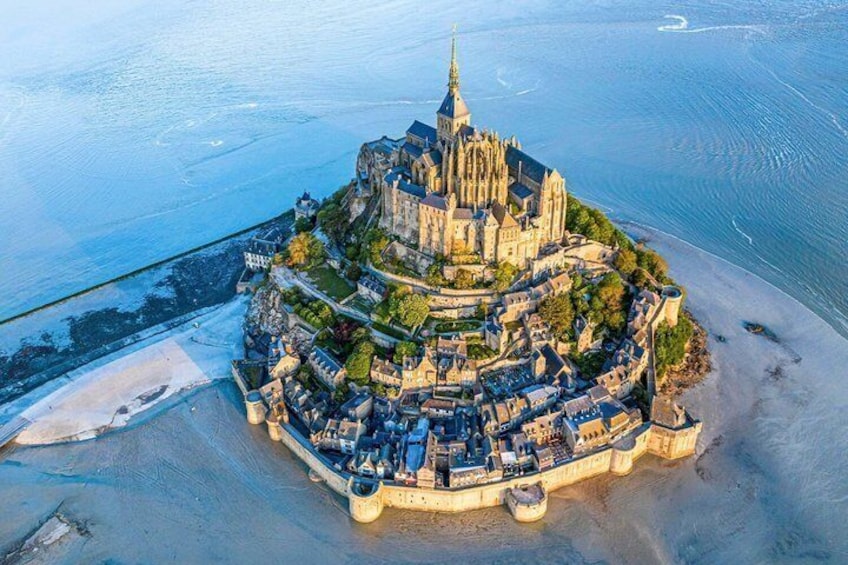 An aerial view of a historic coastal town with a prominent cathedral, a fortified wall, and a beach. 2