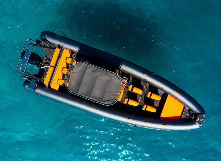 An inflatable boat with yellow seats and a gray canopy, floating on clear blue water. 3