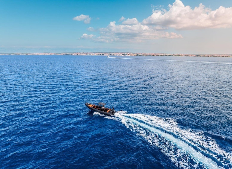 A speedboat on a blue sea with a wake, distant shoreline, and a clear sky. 5