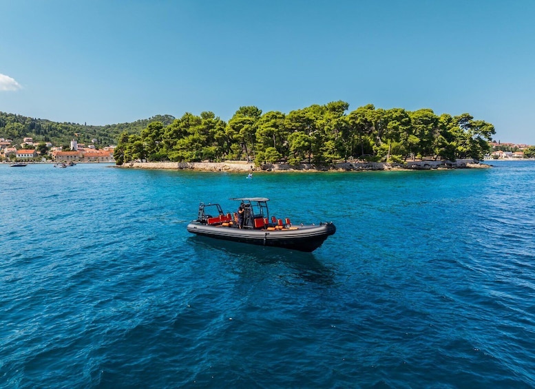A boat on a calm sea with a coastal town and a forested island in the background. 1