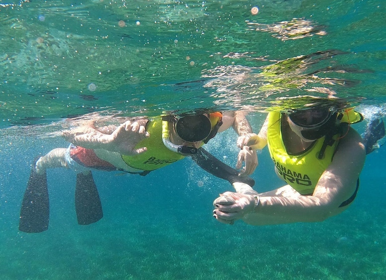 Two people snorkeling underwater, wearing yellow life vests and goggles. 2