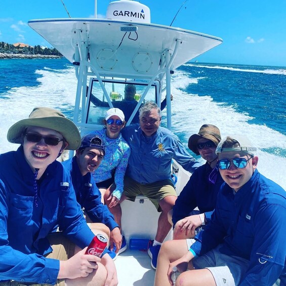 A group of people on a boat with a Garmin logo, wearing blue jackets, and one person holding a can of Coca-Cola. 4