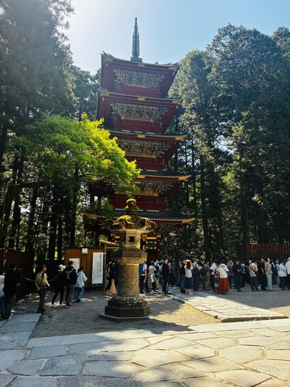 A traditional multi-tiered pagoda surrounded by a forested area with visitors. 5