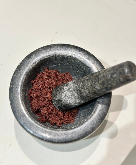 A mortar with a pestle and a pile of brown powder. 2