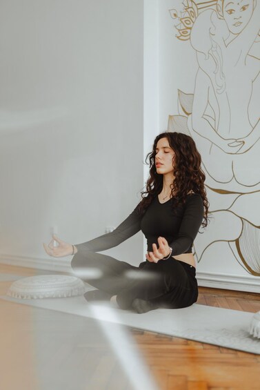 A person meditating on a yoga mat in a room with a wall mural. 2