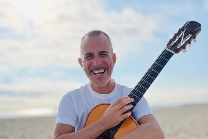 A person holding a guitar on a beach. 5