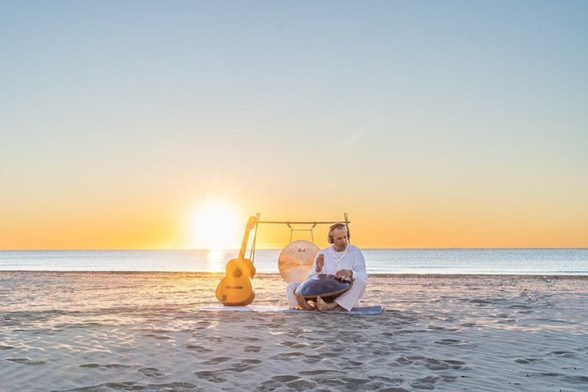A person sitting on the beach with a guitar and a surfboard. 2