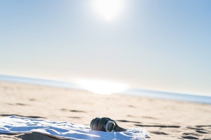 A beach with a camera on the sand and the sun in the background. 5