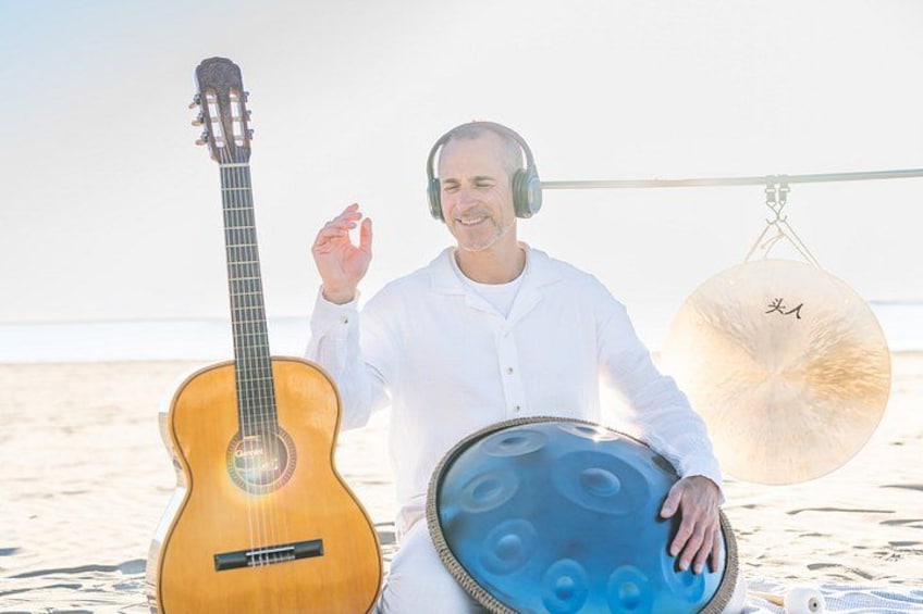 A person holding a guitar and a tambourine on a beach. 3