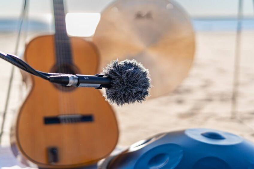 A guitar and a microphone on a beach. 4