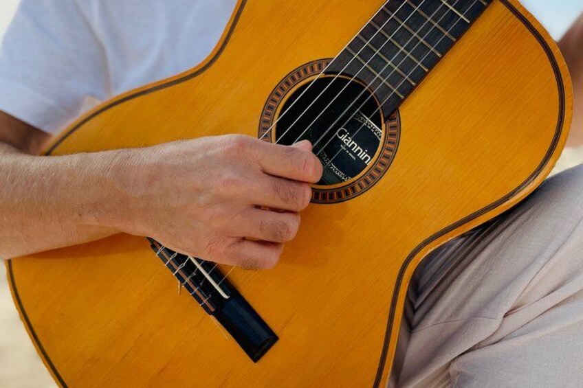 A person holding an acoustic guitar with a black pick. 2