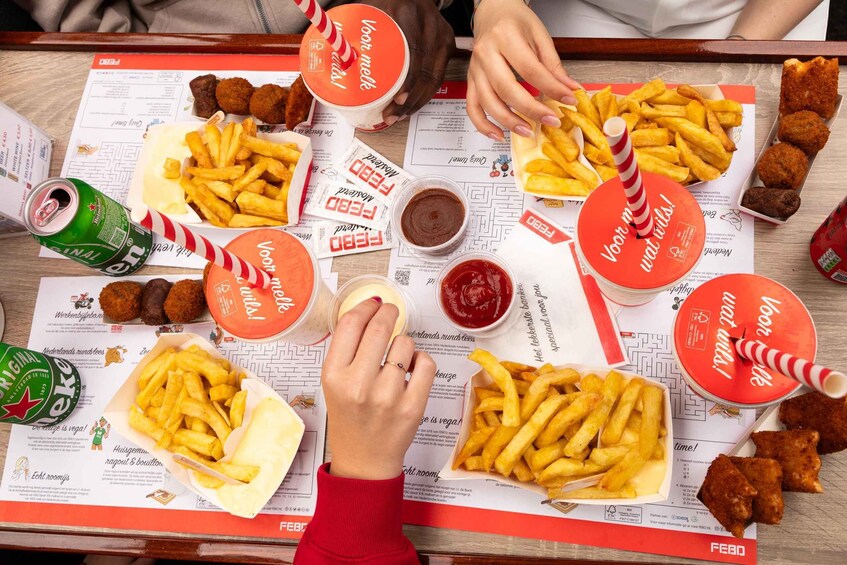 A table with various food items including fries, breaded items, and drinks, with menus and branded containers. 2