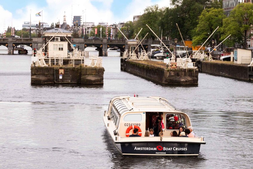 A boat named 'Amsterdam Boat Cruises' on a river with a bridge and buildings in the background. 4