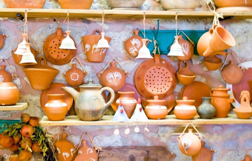 A variety of terracotta pottery items displayed on shelves against a stone wall. 5