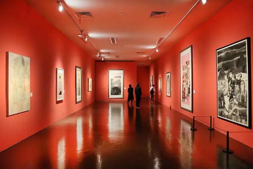 An art gallery with red walls and a polished floor, featuring various framed artworks on display. 5