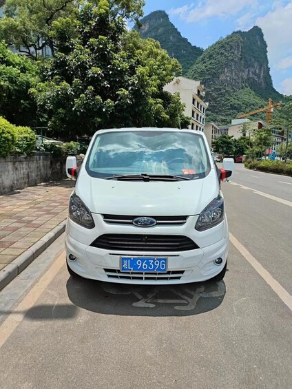 A white car parked on a road with a mountainous backdrop. 3