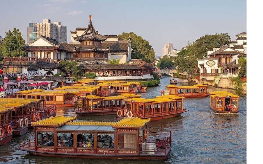 Traditional yellow-roofed boats on a river, surrounded by historic buildings. 1