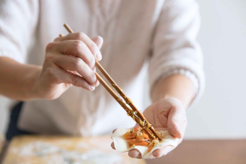 A person using chopsticks to pick up food from a plate. 1