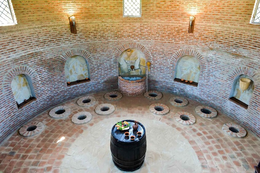 A brick-walled room with arched niches and a central hearth. 4