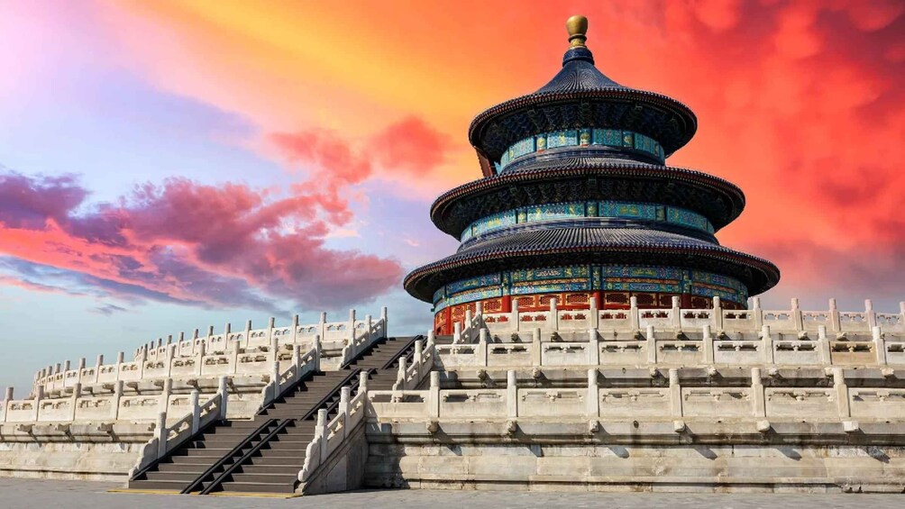 A traditional Chinese pagoda with a multi-tiered roof, surrounded by a stone railing and stairs leading up to it. 2
